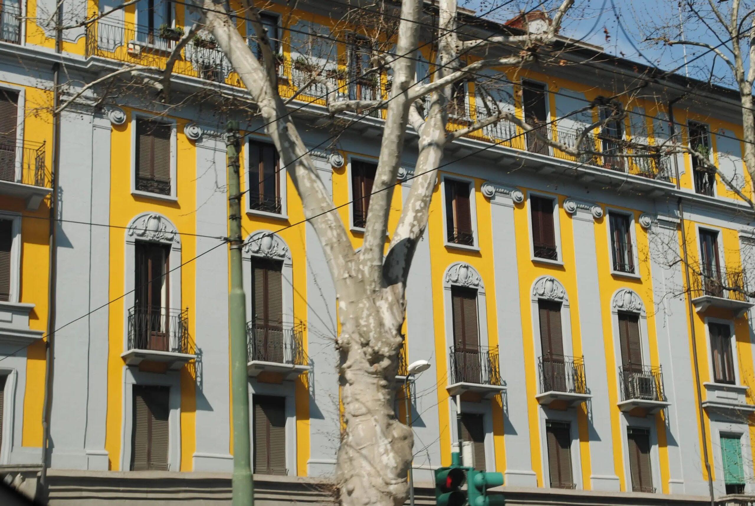 Milano e il colore 2 - Artemisia Palazzo giallo a Milano con finestre e balconi decorati.